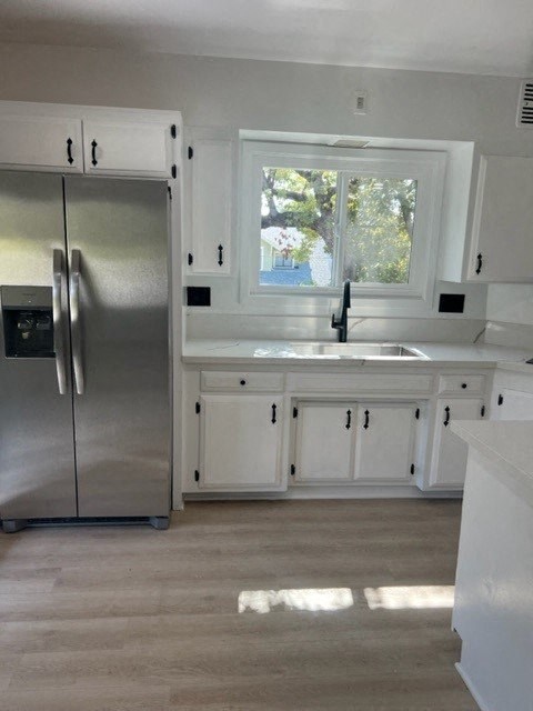 a kitchen with white cabinets and a stainless steel refrigerator